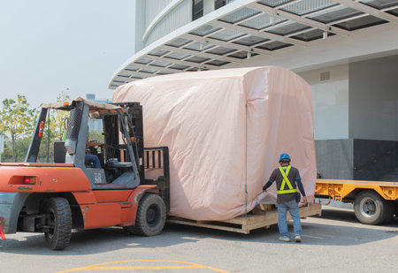 Orange forklift is lifting train head for driving simulation , covering the pink cloth, move from...
