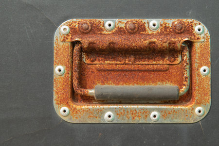 The pattern of red rust on steel handle of an old black wooden box in yard. have nut and Scratches...