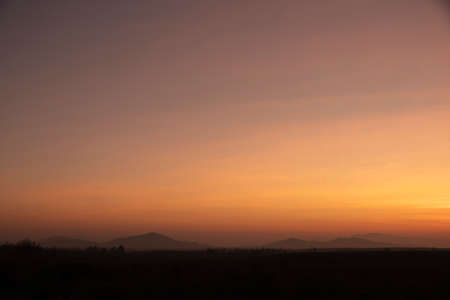Morning blur over mountains and trees. The first and last light of the day in sky with beautiful red and yellow clouds sunlight as  background. have white fog around. concept village in mountain.の写真素材