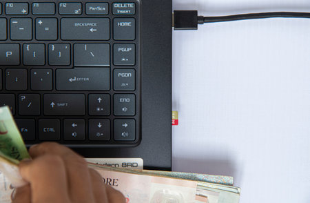 Top view black keyboard on notebook have  banknote in hand, and a memory card plugged into computer on white background have space for text. business online concept, make money online next generation.の写真素材