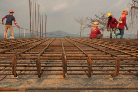 Blur red rusty on rebar  as structural steel for the floor to pour concrete, there is a background of workers tying wire to iron mountains and the sky are far away.の写真素材