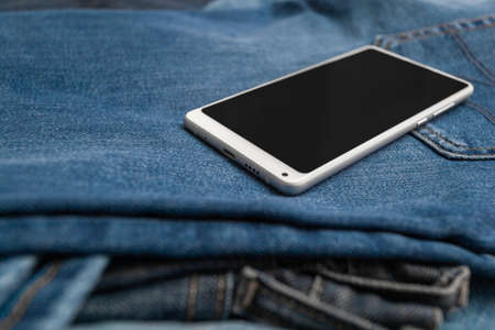 white mobile phone on blue jeansの写真素材