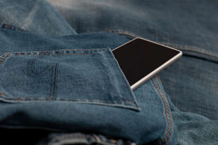 white mobile phone on blue jeansの写真素材