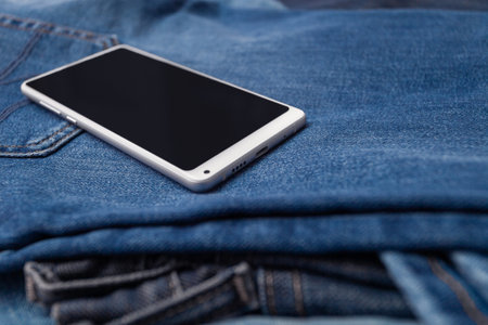 white mobile phone on blue jeansの写真素材