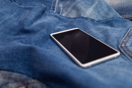 white mobile phone on blue jeansの写真素材