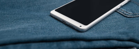 panorama white mobile phone on blue jeansの写真素材