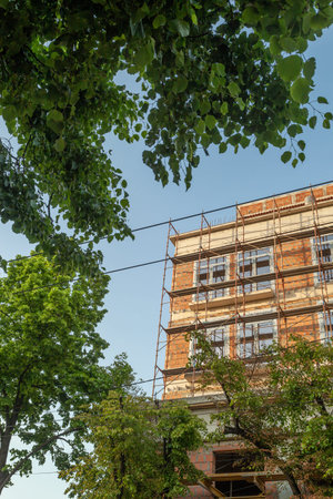 Multi-storey residential building under construction and crane on a background of blue sky