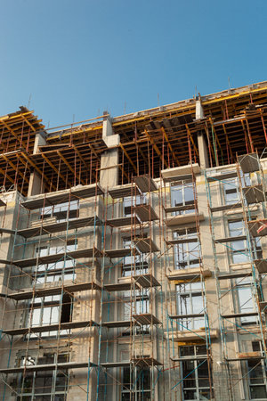 Multi-storey residential building under construction and crane on a background of blue sky