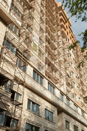 Multi-storey residential building under construction and crane on a background of blue skyの写真素材