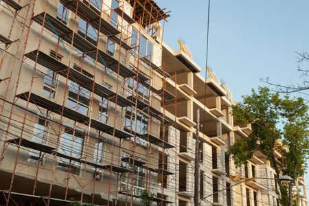Multi-storey residential building under construction and crane on a background of blue skyの写真素材