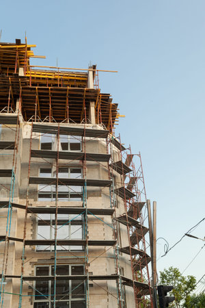 Multi-storey residential building under construction and crane on a background of blue sky