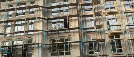 Panorama of a multi-storey residential building under construction and crane on a background of blue...