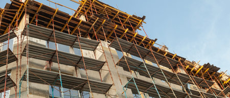 Panorama of a multi-storey residential building under construction and crane on a background of blue...