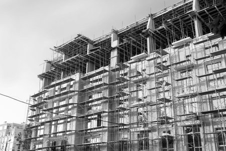 Black and white photo of a multi-storey residential building under construction and crane on a...