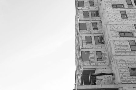 Black and white photo of a multi-storey residential building under construction and crane on a...