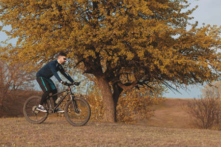cyclist rides through the autumn forest and parkの写真素材