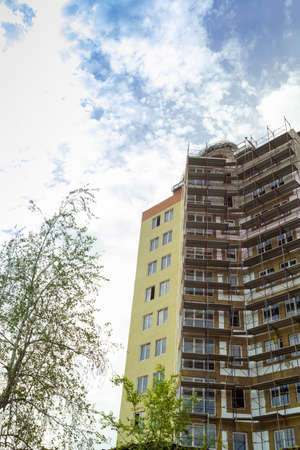 Multi-storey residential building under construction and crane on a background of blue skyの写真素材