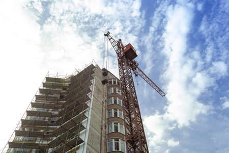 Multi-storey residential building under construction and crane on a background of blue sky