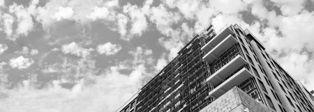 Black and white panorama of a multi-storey residential building under construction and crane on a...