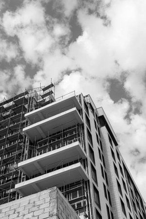 Black and white photo of a multi-storey residential building under construction and crane on a...