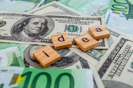idea inscription on wooden cubes on the texture of us dollars and euro banknotesの写真素材