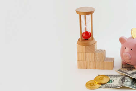 panorama Pig shaped piggy bank with bitcoin coins, hourglass, growing graph wood cubes and us dollars on isolated white backgroundの写真素材