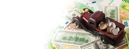 wooden car with coins on euro and dollars texture background panoramaの写真素材
