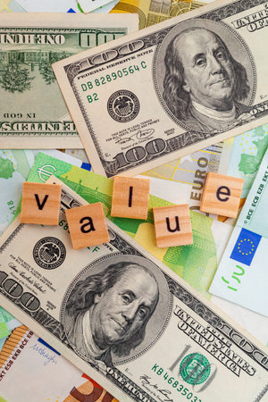 VALUE inscription on wooden cubes on the texture of us dollars and euro banknotes