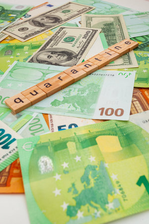 QUARANTINE inscription on wooden cubes on the texture of us dollars and euro banknotes