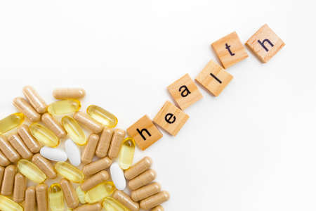 inscription HEALTH in wooden cubes on a white background of different pillsの写真素材