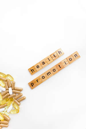 inscription HEALTH PROMOTION in wooden cubes on a white background of different pillsの写真素材