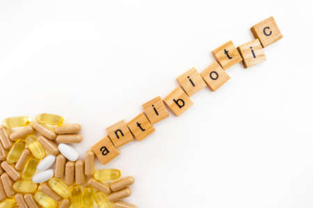 inscription ANTIBIOTIC in wooden cubes on a white background of different pillsの写真素材