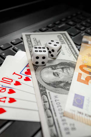 Chisinau, Moldova - 20.12.2020 dice, playing cards on laptop keyboard dollars and euro billsの写真素材