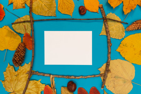 Autumn mockup with yellow, red leaves. Fir cones and a white sheet of paper for the inscription.