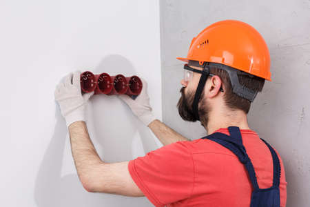 electrician in helmet installs socketsの写真素材