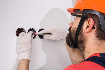 electrician in helmet installs socketsの写真素材