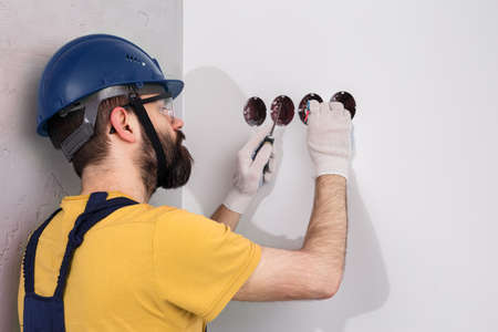electrician in helmet installs socketsの写真素材