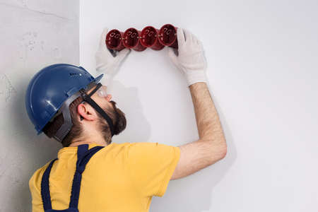 electrician in helmet installs socketsの写真素材