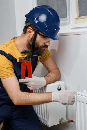 a worker in an orange helmet installs radiators in the houseの写真素材