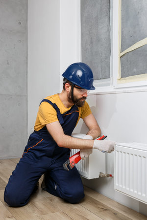 a worker in an orange helmet installs radiators in the house