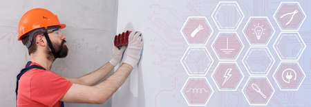 electrician in helmet installs sockets infographicsの写真素材