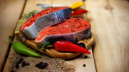 Close up of raw salmon steaks with chilli, herbs and spices on a nice wooden background.の写真素材