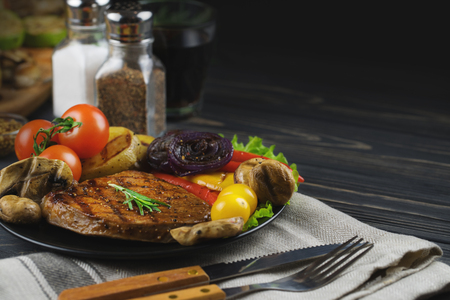 Beef steak with grilled vegetables on a dark wooden table.の写真素材