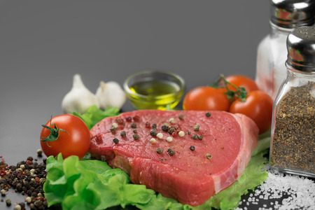 Raw beef steak with vegetables, greens, various spices and olive oil ready to be grilled.の写真素材