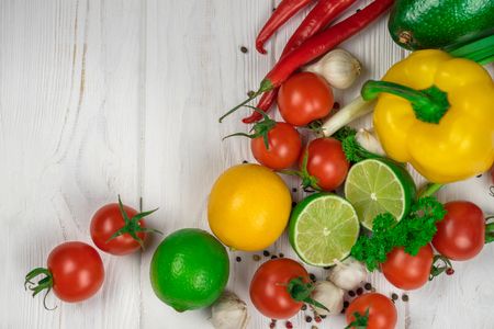 Mix of fresh bright fruits and vegetables on the white wooden background. Healthy eating, vegetarian food concept. Mock up, place for your text.の写真素材