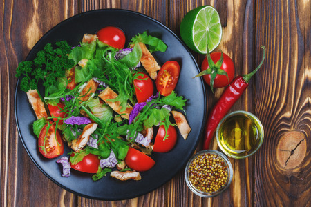 Plate of vegetable salad with grilled chicken on the dark wooden background. Top view.の写真素材