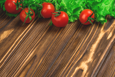 Fresh cherry tomatoes and lettuce on the rustic wooden background. Mock up, copy space for your text.の写真素材