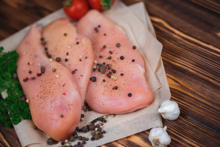 Close up of raw chicken fillet with vegetables and greens on the wooden background.の写真素材