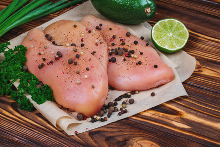 Close up of raw chicken fillet with vegetables and greens on the wooden background.の写真素材