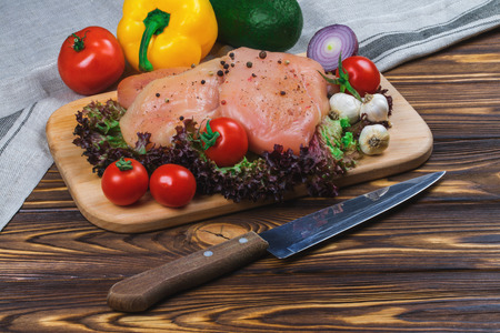 Raw chicken fillet with vegetables and greens on the wooden background.の写真素材